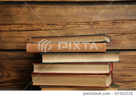 Collection of different books on table against wooden background 93162528