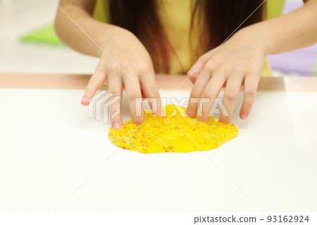 Little girl playing with slime at white table, closeup 93162924