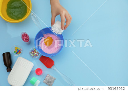 Little girl making slime toy on light blue background, top view. Space for text 93162932