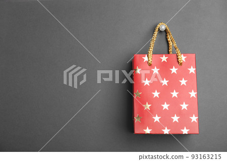 Red shopping paper bag with star pattern on black background, space for text 93163215