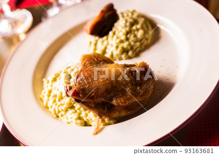 dish duck leg with green perlotto served on a white plate 93163681