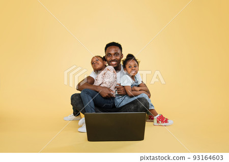 Happy african american daddy and his two little cute daughters spending time together using laptop 93164603