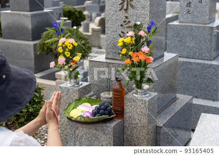 一位中年婦女來掃墓，雙手捧著美麗的鮮花和供品 93165405