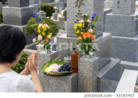 一位中年婦女來掃墓，雙手捧著美麗的鮮花和供品 93165407