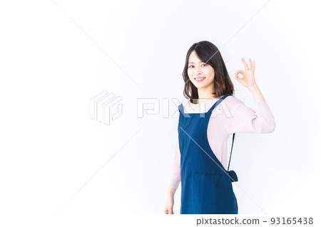 A young woman wearing an apron and showing an OK sign 93165438