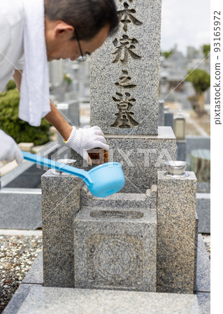 Senior man visiting a grave and cleaning the grave 93165972