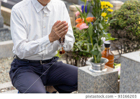 Senior man visiting a grave and putting his hands together 93166203