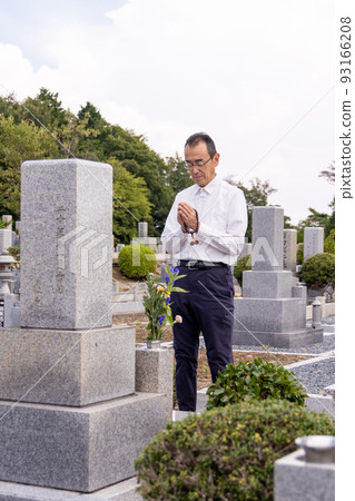 Senior man visiting a grave and putting his hands together 93166208