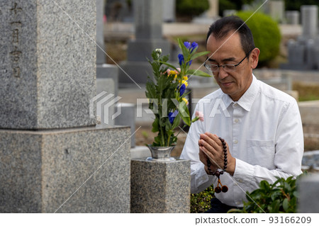 Senior man visiting a grave and putting his hands together 93166209