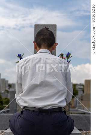 Senior man visiting a grave and putting his hands together 93166210