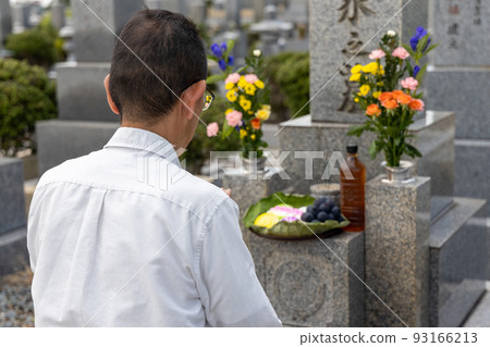 Senior man visiting a grave and putting his hands together 93166213