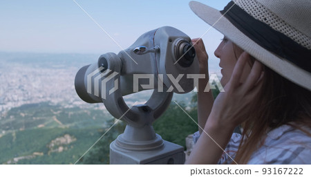 Woman traveler looking at city view, close-up. Beautiful woman in hat, on observation watching through telescope at city Tirana panorama. Mountain Dajti, Albania 93167222