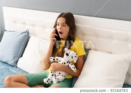 Is that a fact. Surprised girl talk on phone holding puppy toy. Informal phone call Is that a fact. Surprised girl talk on phone holding puppy toy. Informal phone call 93168763