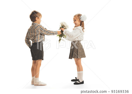 Portrait of children, boy giving girl flowers isolated over white studio background. Retro fashion Portrait of children, boy giving girl flowers isolated over white studio background. Retro fashion 93169336