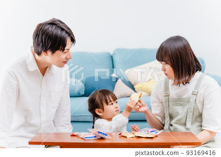 Parent and child eating sweets in the living room Parent and child eating sweets in the living room 93169416