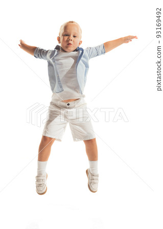 Portrait of little boy, child in casual outfit posing isolated over white studio background. Cheerfully jumping, playing Portrait of little boy, child in casual outfit posing isolated over white studio background. Cheerfully jumping, playing 93169492