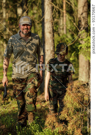 Father and son in military clothes spending time together in the woods. The concept of adventure, travel, tourism and camping 93170667