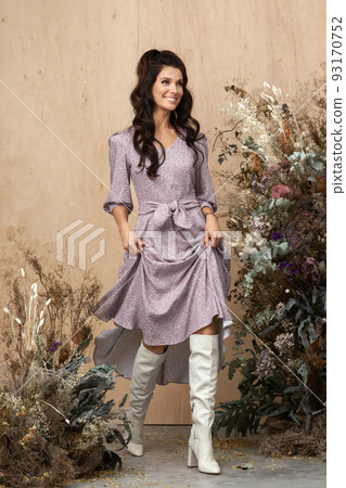 Studio autumn fashion portrait of beautiful confident woman with long brown hair wearing stylish trendy clothes in earth tones and posing over wood Background decorated with dried flowers. Autumn Studio autumn fashion portrait of beautiful confident woman with long brown hair wearing stylish trendy clothes in earth tones and posing over wood Background decorated with dried flowers. Autumn 93170752