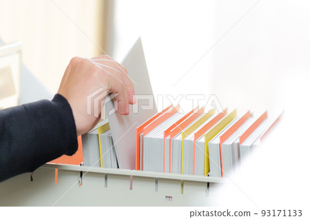 Close up of a hand searching for documents in a desk drawer Close up of a hand searching for documents in a desk drawer 93171133