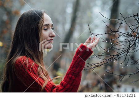Improving mental wellbeing, Relax and reduce stress. young woman in red sweater touching water drops on tree branches Improving mental wellbeing, Relax and reduce stress. young woman in red sweater touching water drops on tree branches 93171221