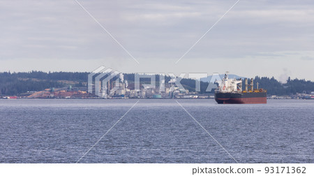 Industrial Processing Plant and Container Ship passing by on a cloudy day. 93171362