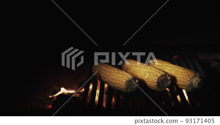 Cooking on an open fire - delicious corn is fried on a hot grill in the grill Cooking on an open fire - delicious corn is fried on a hot grill in the grill 93171405