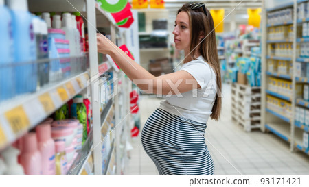 Baby shampoo pregnancy woman buy. Young pregnant woman shopping on baby bath shampoo bottle on supermarket background. Baby cosmetic shop choice. Baby shampoo pregnancy woman buy. Young pregnant woman shopping on baby bath shampoo bottle on supermarket background. Baby cosmetic shop choice. 93171421