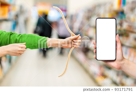 Females hands hold a hanger in the form of a hunting bow. Side view. Cellphone with mock up. Concept of sale and hunting for discounts Females hands hold a hanger in the form of a hunting bow. Side view. Cellphone with mock up. Concept of sale and hunting for discounts 93171791