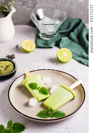 Vegetarian popsicle made from matcha tea, coconut milk and mint on a plate. Vertical view 93172257