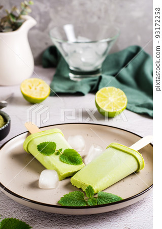 Vegetarian popsicle made from matcha tea, coconut milk and mint on a plate. Vertical view. Close-up Vegetarian popsicle made from matcha tea, coconut milk and mint on a plate. Vertical view. Close-up 93172258