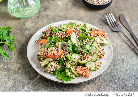Appetizing salad of cucumbers, tomatoes, a mixture of quinoa and parsley on a plate on the table. 93172284