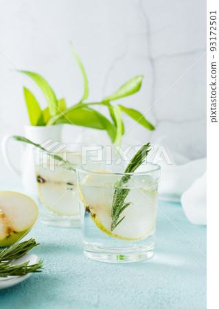 Cold cocktail of pear slices and mineral water in glasses on the table. Homemade drinks. Vertical view 93172501