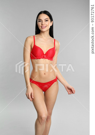 Beautiful young woman in red underwear on grey background Beautiful young woman in red underwear on grey background 93172761