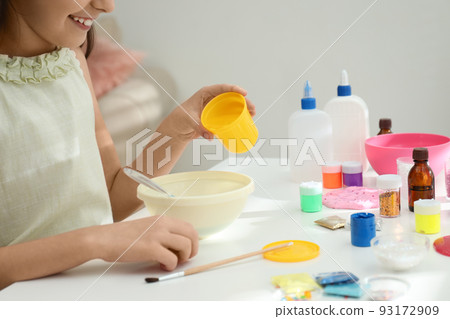Little girl making homemade slime toy at table, closeup 93172909