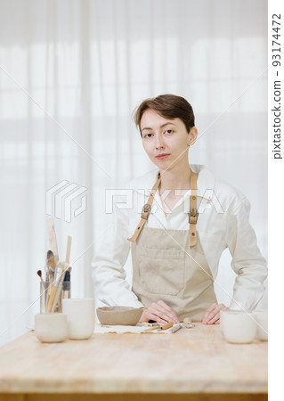 woman ceramist in the workshop makes mugs out of clay. small business or hobby is the creation of ceramic products woman ceramist in the workshop makes mugs out of clay. small business or hobby is the creation of ceramic products 93174472