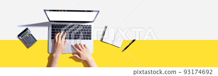 Person using a laptop computer with a notebook Person using a laptop computer with a notebook 93174692