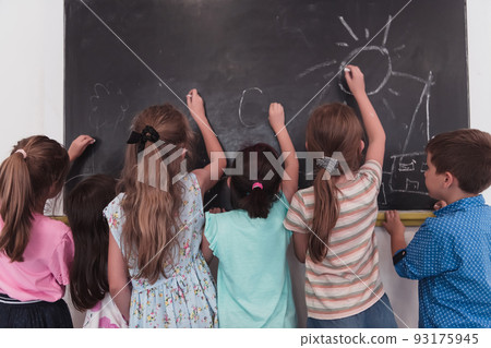 Children write and draw on the blackboard in elementary school while learning the basics of education 93175945