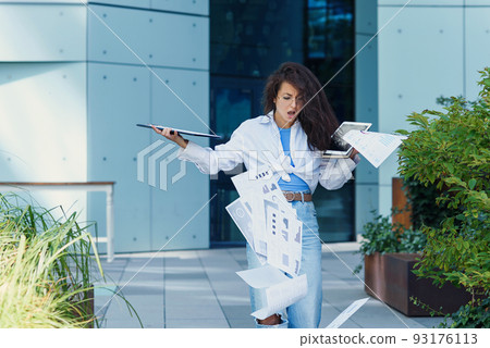 Young business woman dropping paper documents on the floor. Occasion near office building. Young business woman dropping paper documents on the floor. Occasion near office building. 93176113