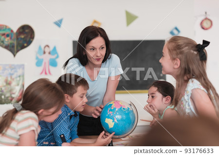 Female teacher with kids in geography class looking at globe. Side view of group of diverse happy school kids with globe in classroom at school. Female teacher with kids in geography class looking at globe. Side view of group of diverse happy school kids with globe in classroom at school. 93176633