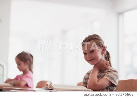 Little girls sitting in elementary school drawing on paper with their friends while sitting in a modern classroom 93176662