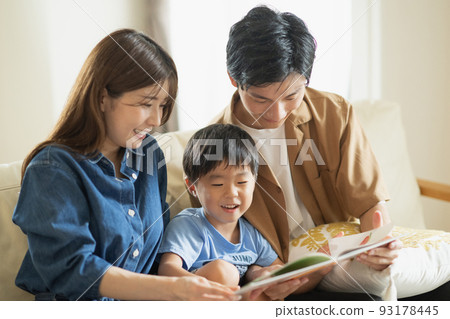 A smiling Japanese family sitting on the sofa, a family looking at a picture book A smiling Japanese family sitting on the sofa, a family looking at a picture book 93178445