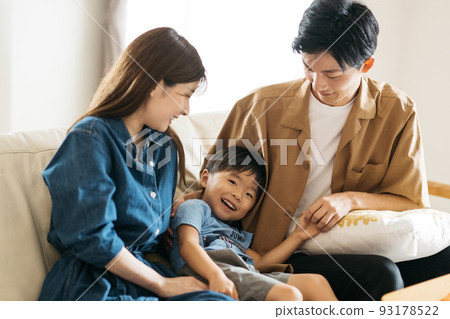 A smiling Japanese family sitting on the sofa / Child-rearing family image A smiling Japanese family sitting on the sofa / Child-rearing family image 93178522