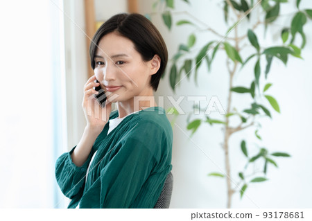 Woman talking on smartphone [living room] 93178681