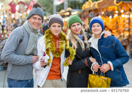 Portrait of happy family with christmas tinsel and gifts at street fair 93178760