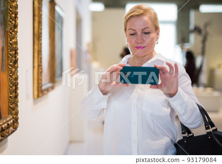 Female visitor taking picture in art gallery Female visitor taking picture in art gallery 93179084