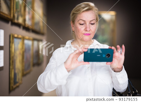 Female visitor taking picture in art gallery Female visitor taking picture in art gallery 93179155
