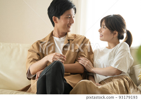 Cohabitation / newlywed image, smiling couple sitting on sofa 93179193