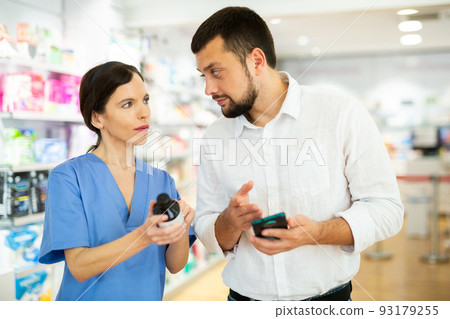 Female pharmacist consulting male customer in drugstore Female pharmacist consulting male customer in drugstore 93179255