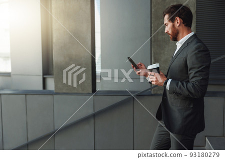 Handsome businessman goes down stairs with coffee and phone during break near office 93180279
