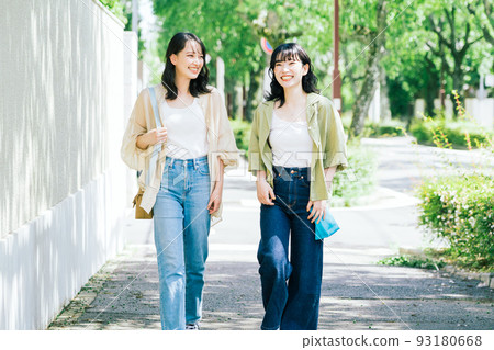 Female friends walking while chatting 93180668